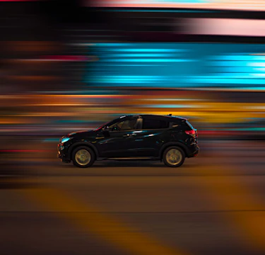 Close-up frame from a Nissan commercial featuring sleek car motion against urban night lights.