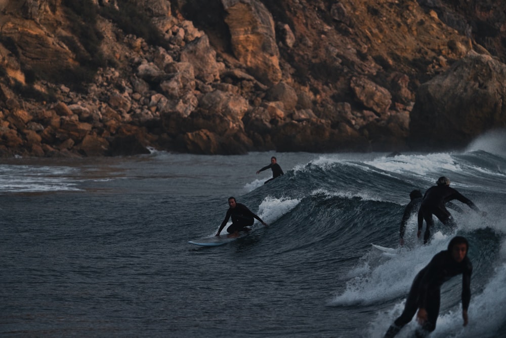 a group of people riding surfboards on top of a wave