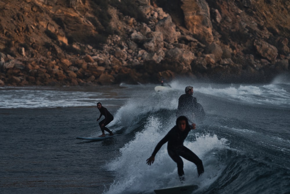 a group of people riding surfboards on top of a wave