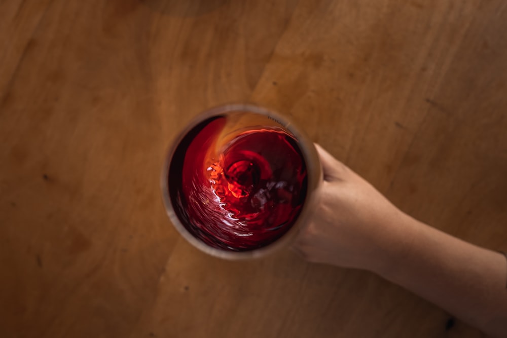 una persona sosteniendo una copa de vino encima de una mesa de madera