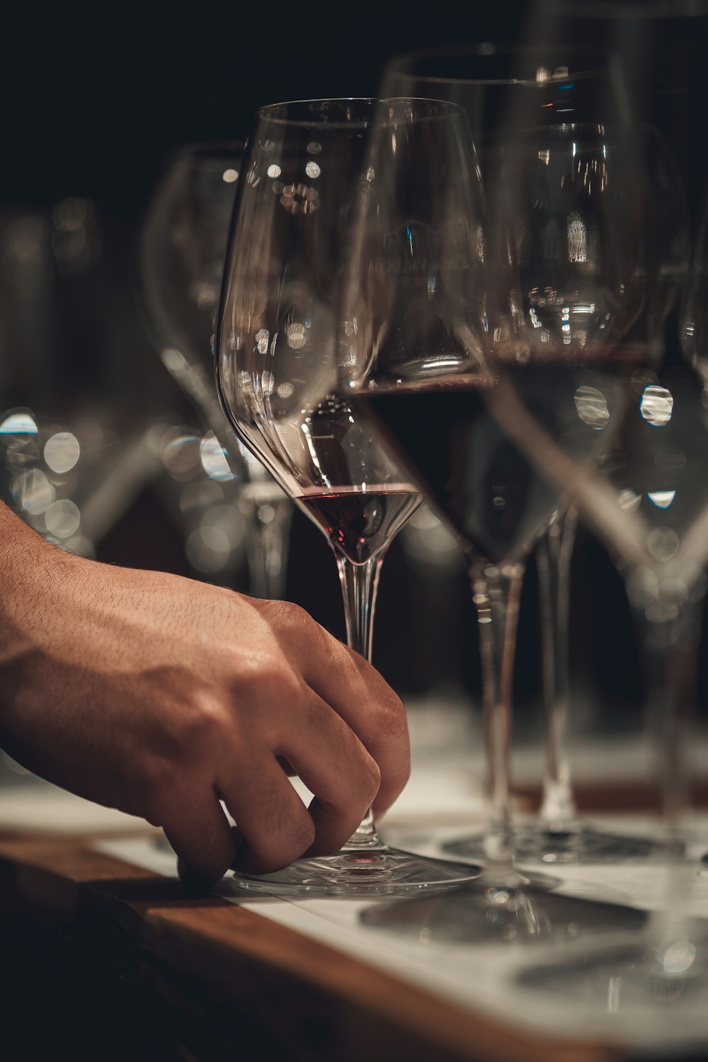 a person's hand touching a glass of wine