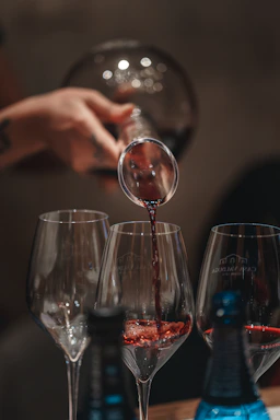 Elegant close-up of a hand pouring aged wine into a crystal glass in a dimly lit, luxurious setting.
