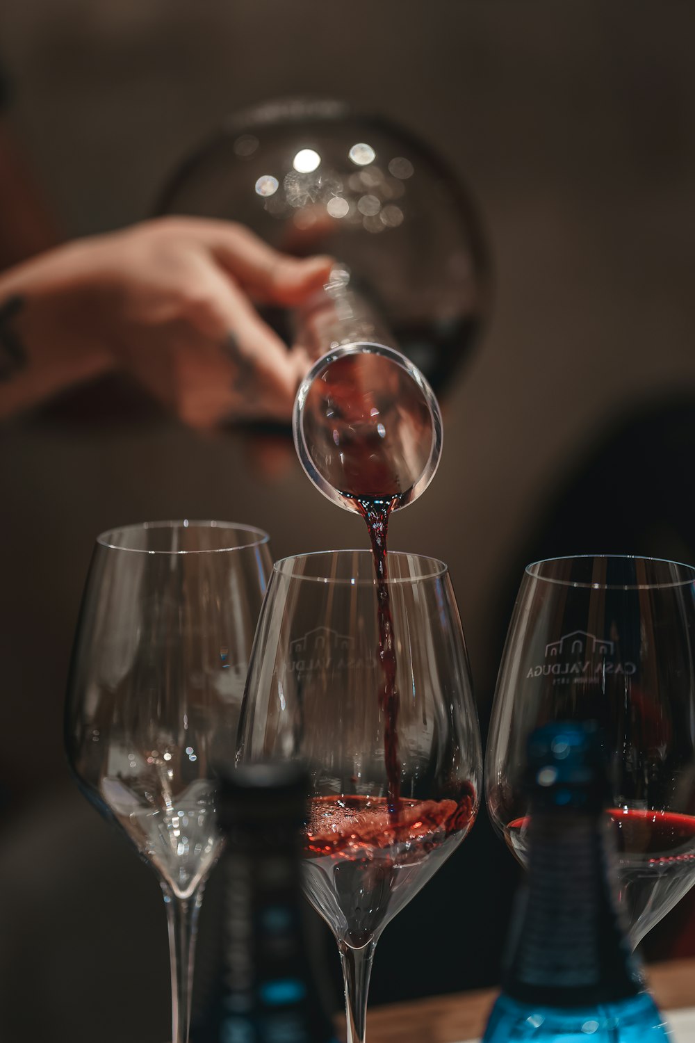a person pouring red wine into wine glasses