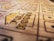 A close-up view of a wooden boardgame surface with engraved patterns, including the words 'FULL HOUSE' and various sections marked with stylized dots resembling dice. The focus is shallow, highlighting the text and some dot patterns while the rest of the board fades softly into the background.