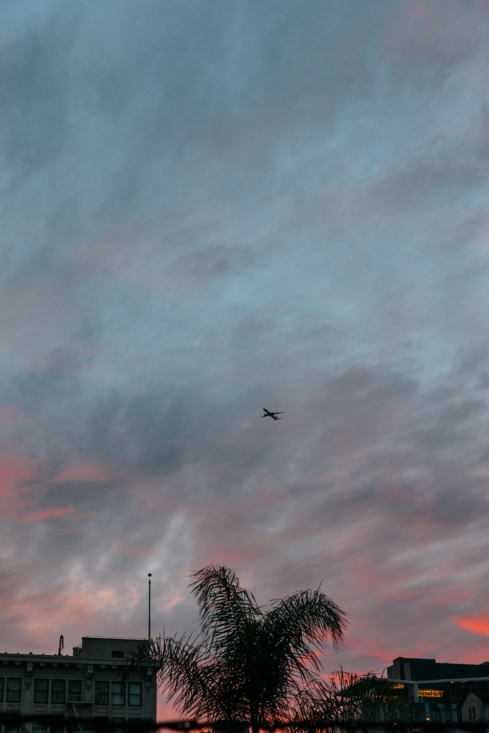 a plane flying in the sky at sunset