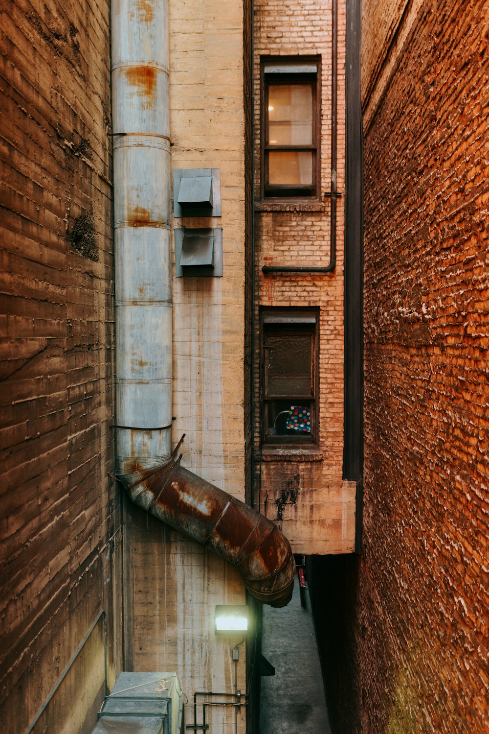 a narrow alley way with a rusted metal pipe