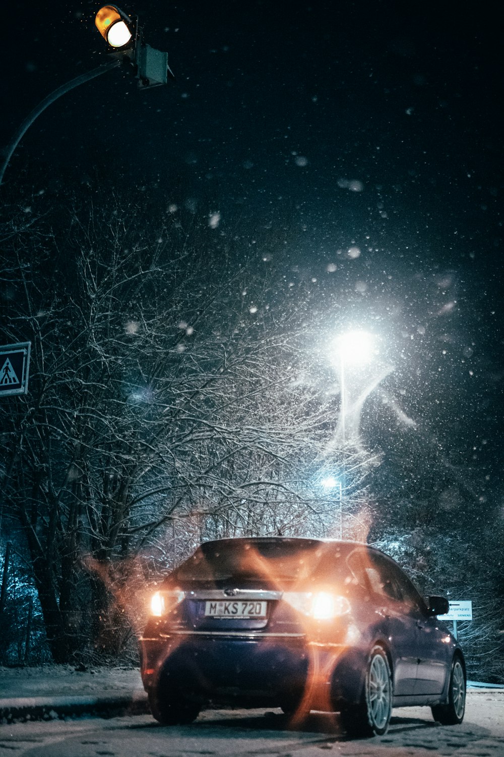 a car driving down a snowy street at night