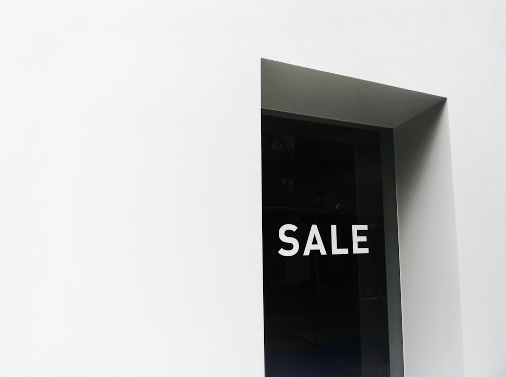 a black and white sale sign on a white wall