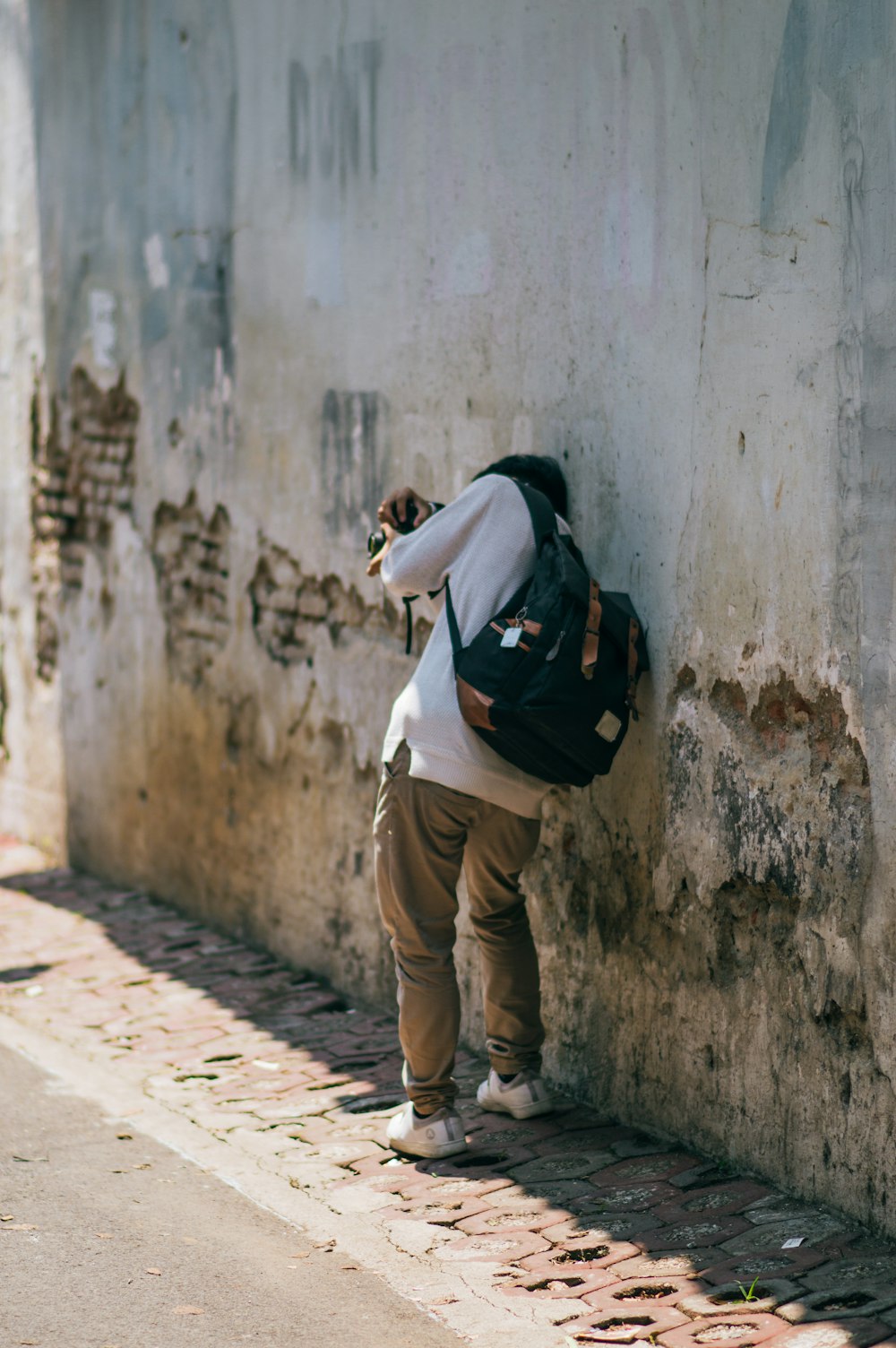 a person leaning against a wall with a backpack