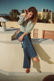 a woman sitting on a ledge with her legs crossed
