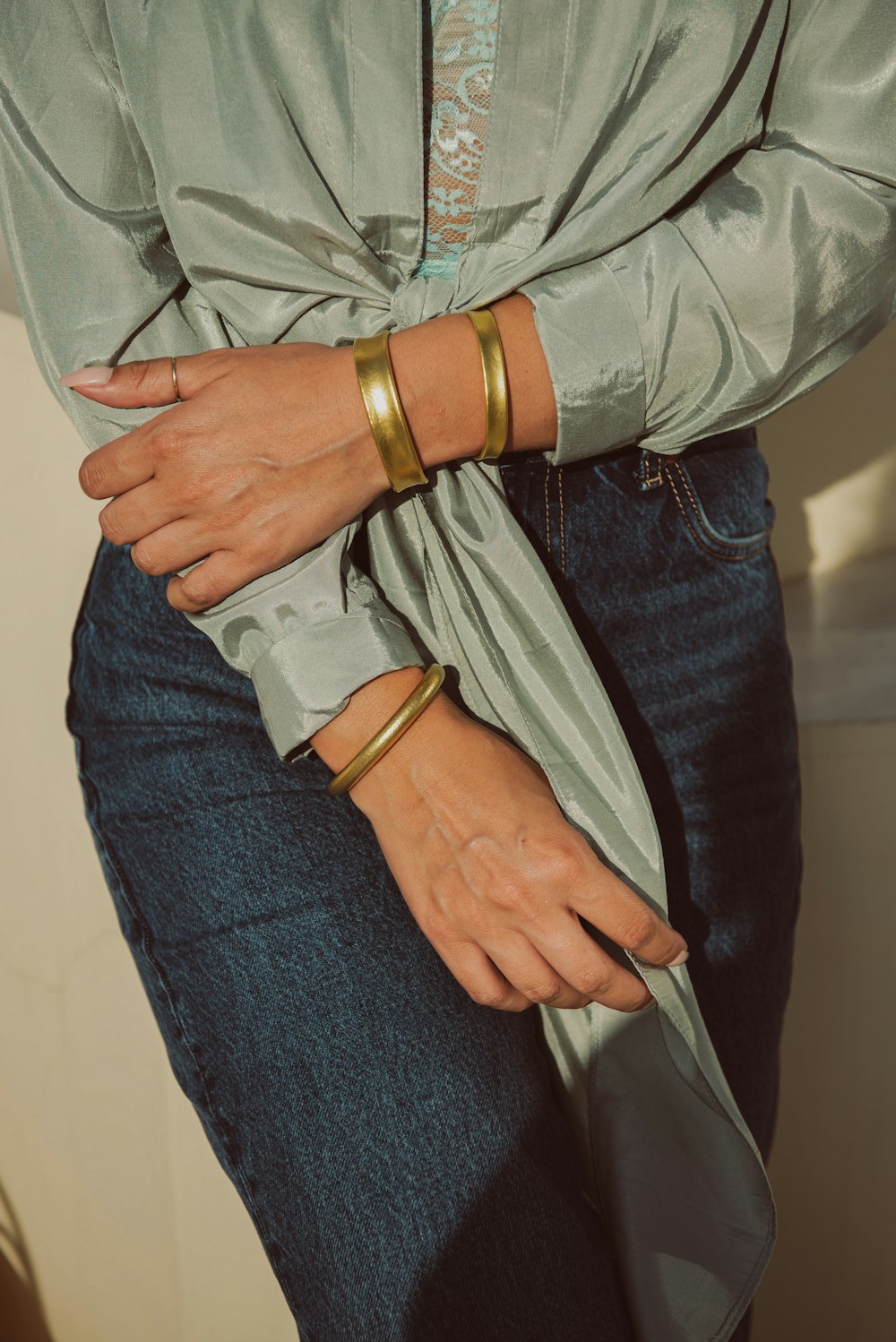 a woman wearing two gold bracelets on her wrist