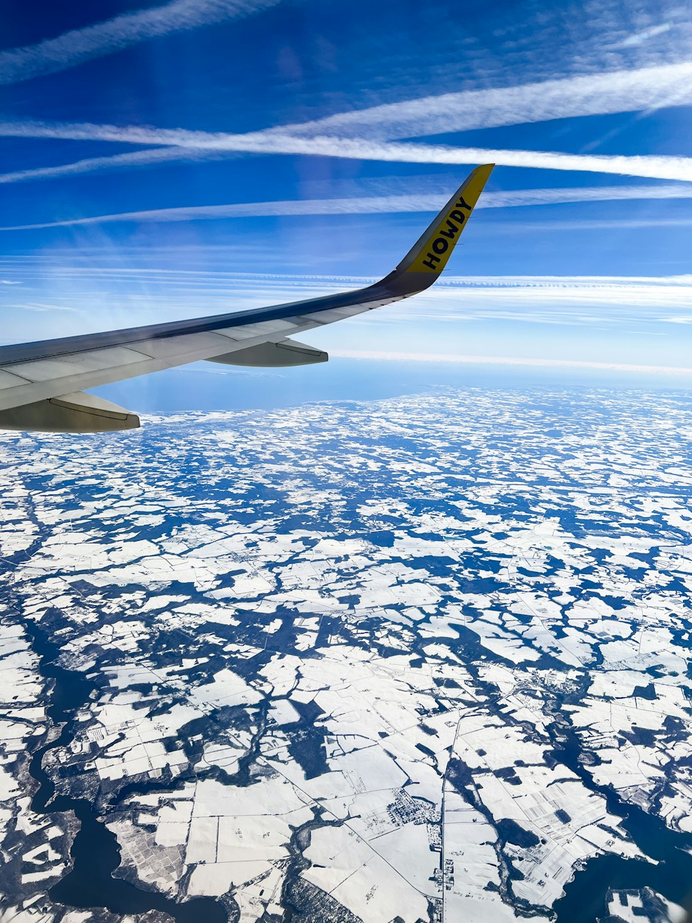 a view of the wing of an airplane flying over ice floes