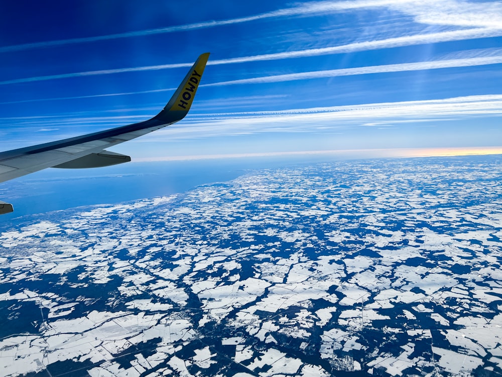 a view of the wing of an airplane as it flies over ice floes