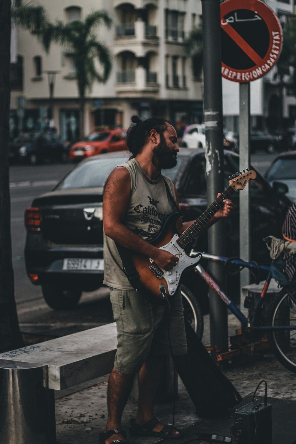 a man playing a guitar next to a street sign