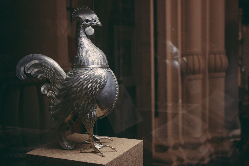 a metal rooster on display in a glass case