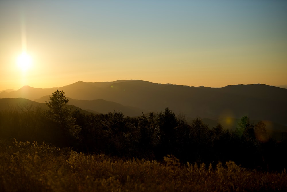 the sun is setting over a mountain range