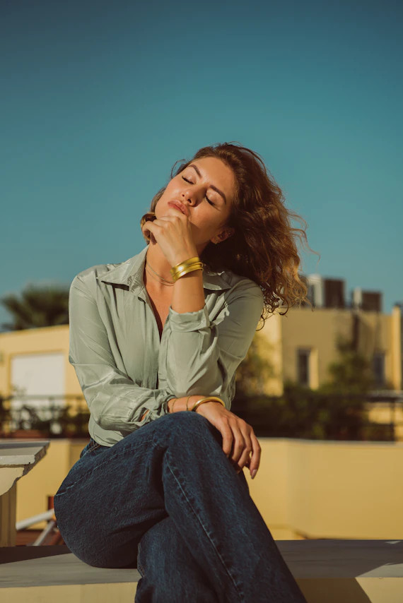 a woman sitting on a ledge with her eyes closed