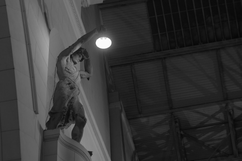 a black and white photo of a statue on the side of a building