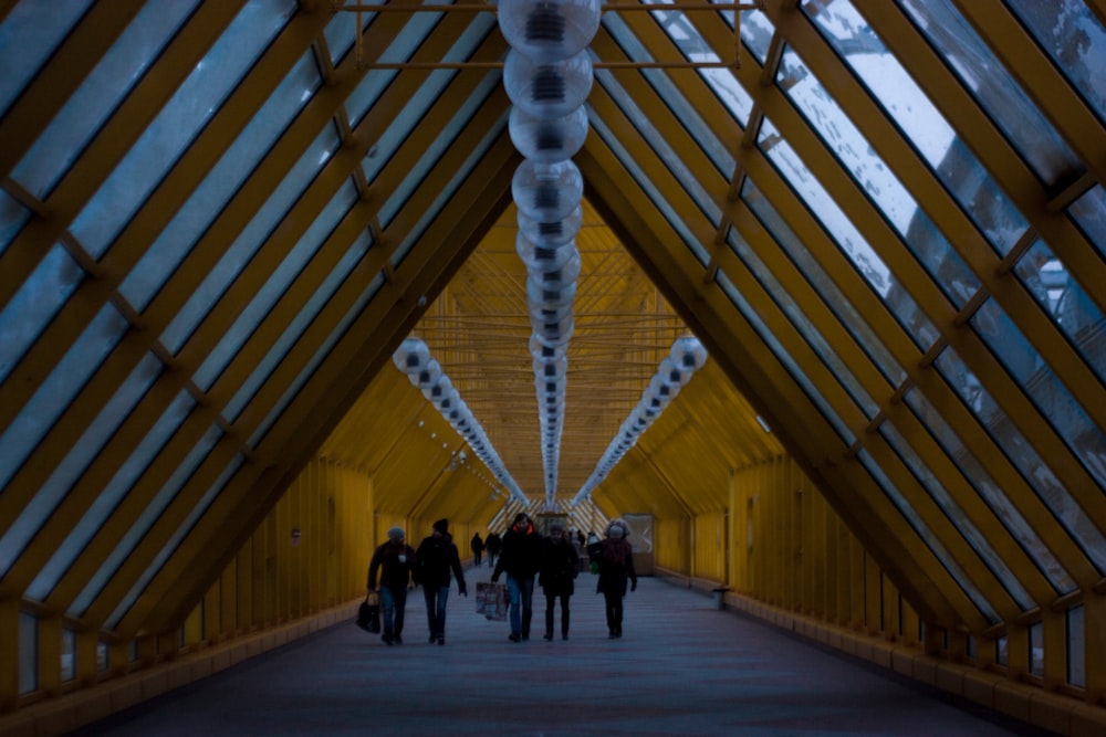 a group of people walking down a walkway in a building