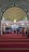 An ornate, Islamic architectural interior with a series of green and gold archways featuring intricate Arabic calligraphy. A chandelier hangs from the ceiling. People are seated on a red carpet, some are standing, indicating a gathering or prayer session.