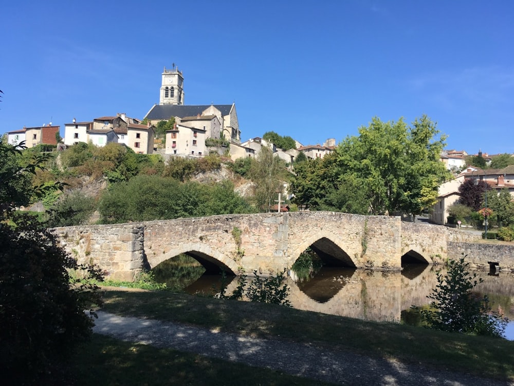 a stone bridge over a river with a church in the background