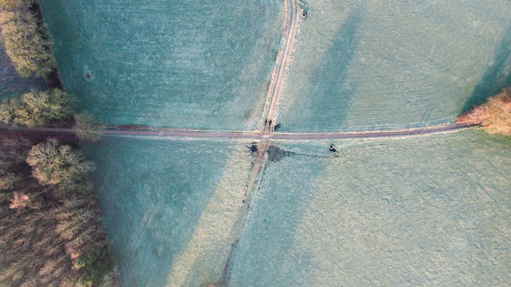 an aerial view of two people walking across a bridge