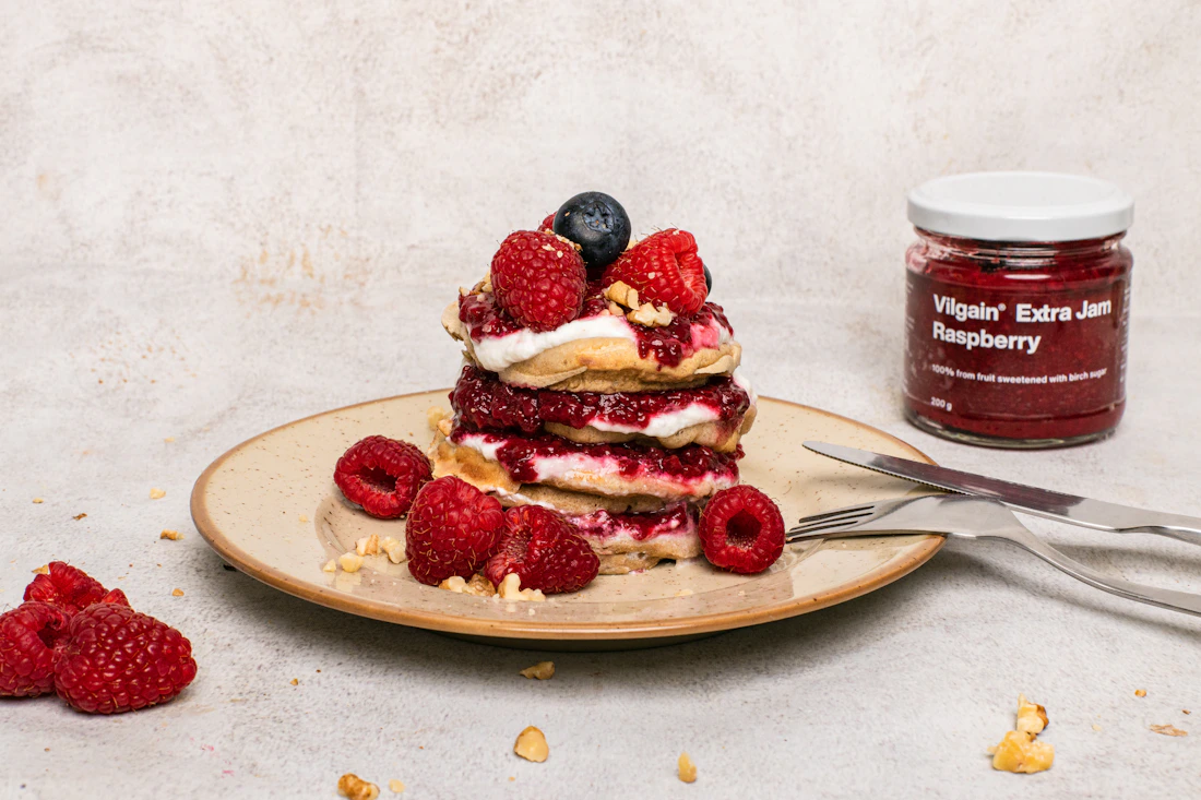A stack of fluffy pancakes decorated with berries and cream