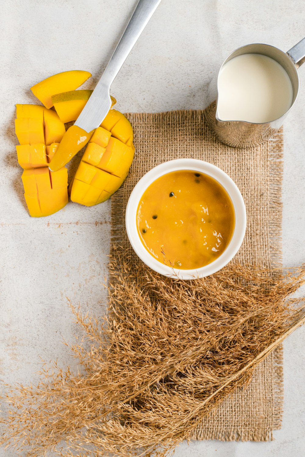 a bowl of mango soup next to a glass of milk