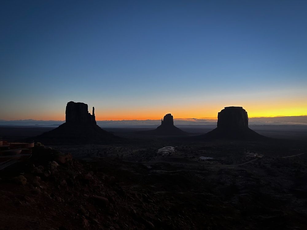 the sun is setting over the desert with mountains in the background