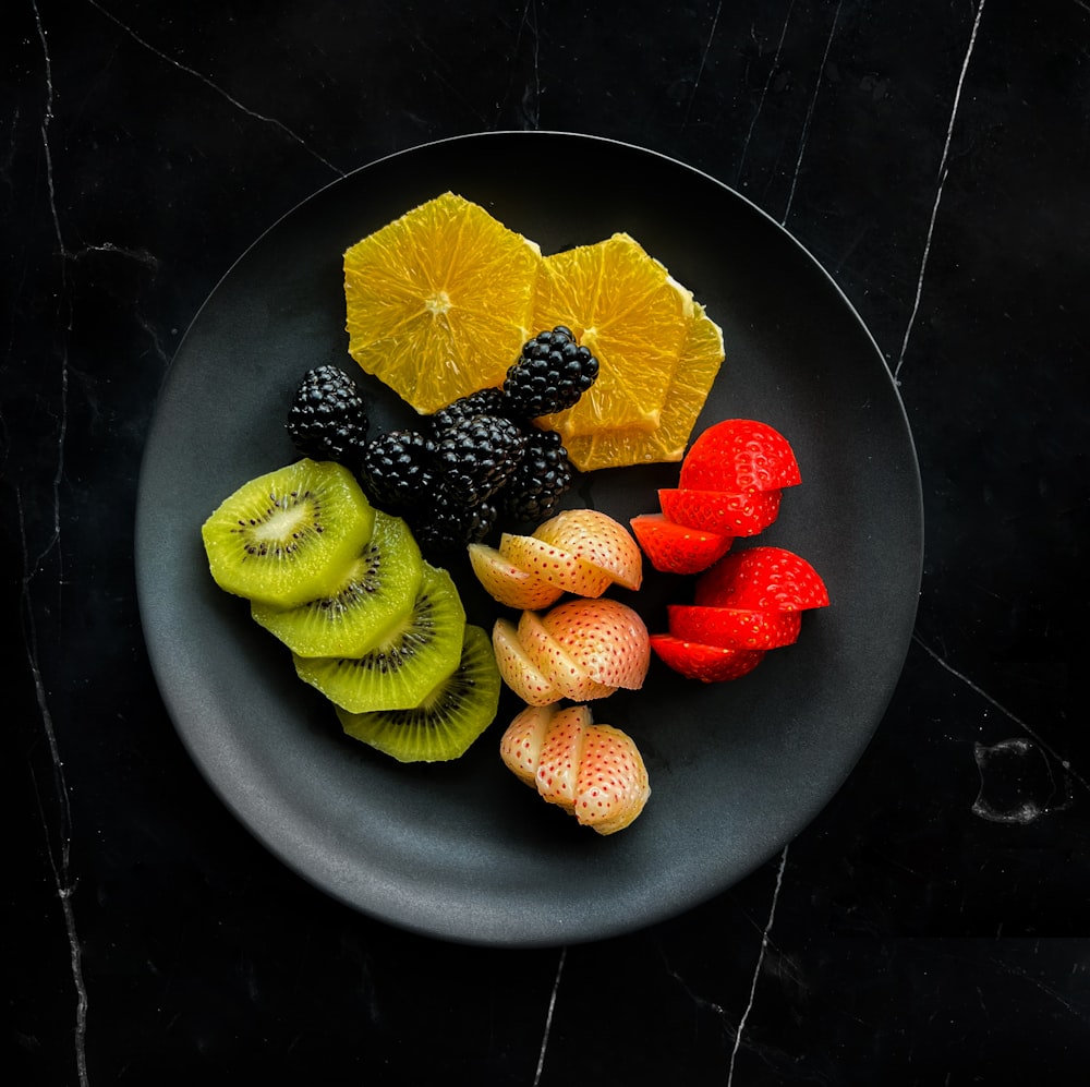 a black plate topped with cut up fruit