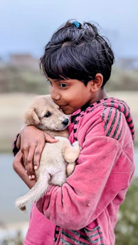 a young boy holding a puppy in his arms