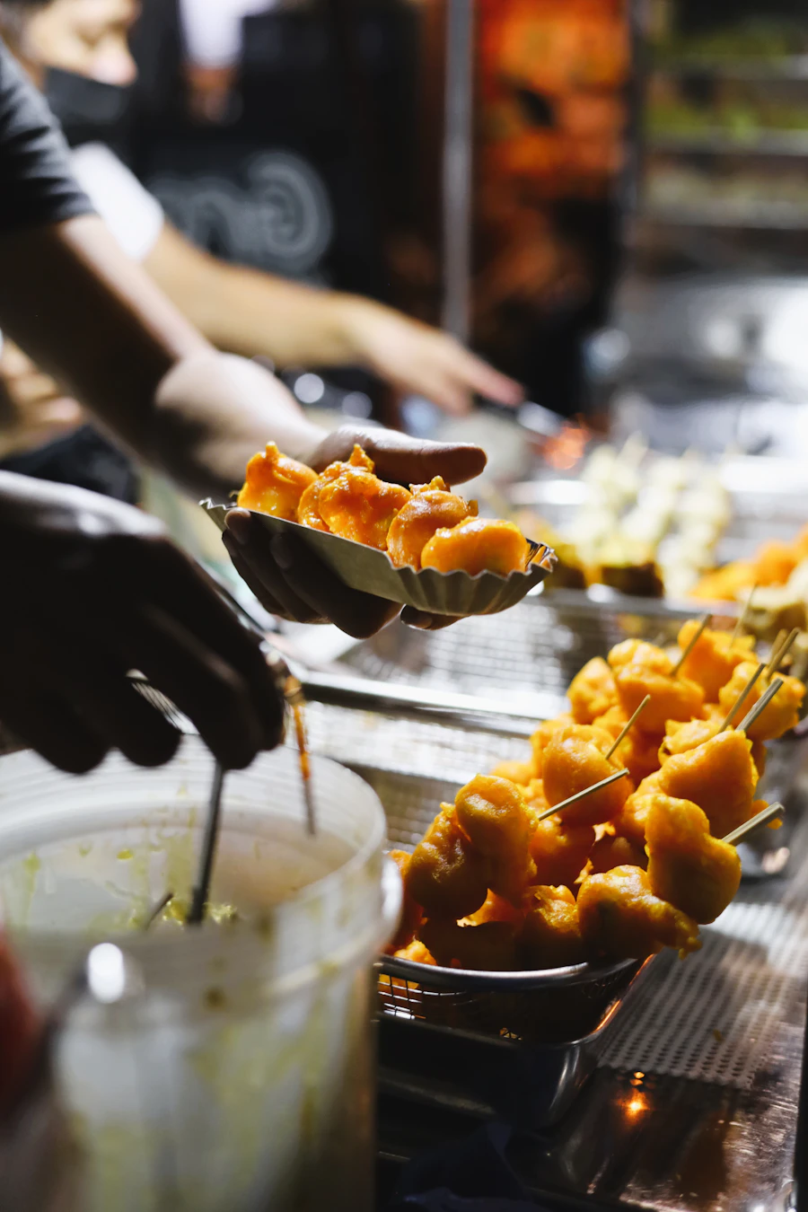 Skewers of fried food being picked from a loaded tray