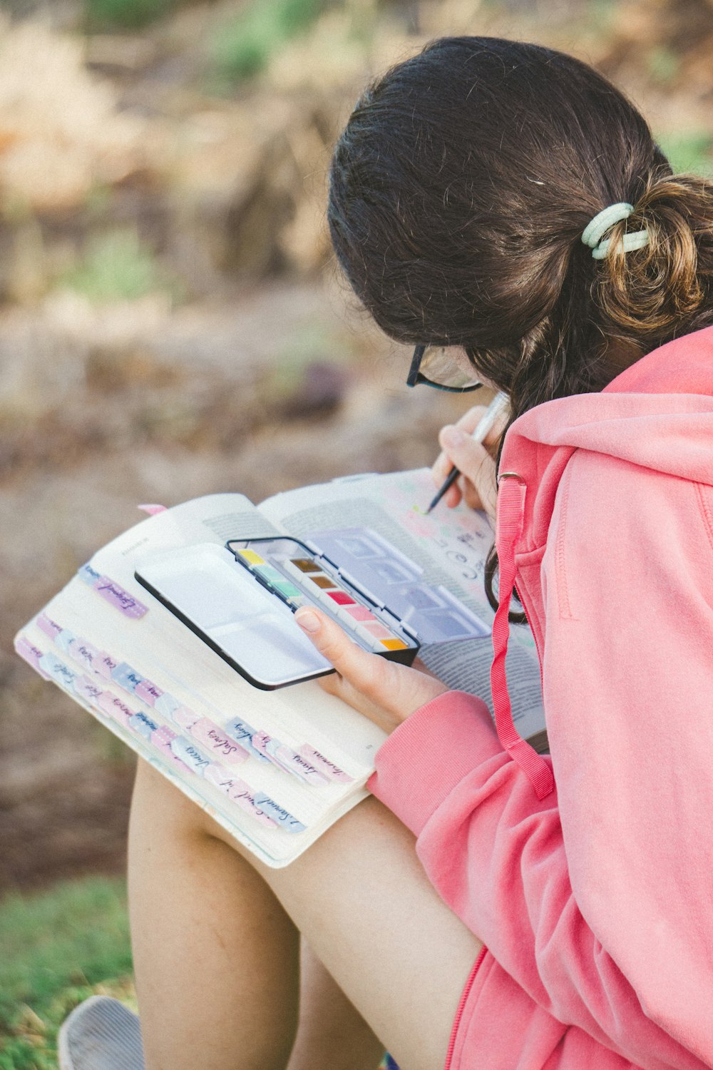 a girl sitting on the ground with a book