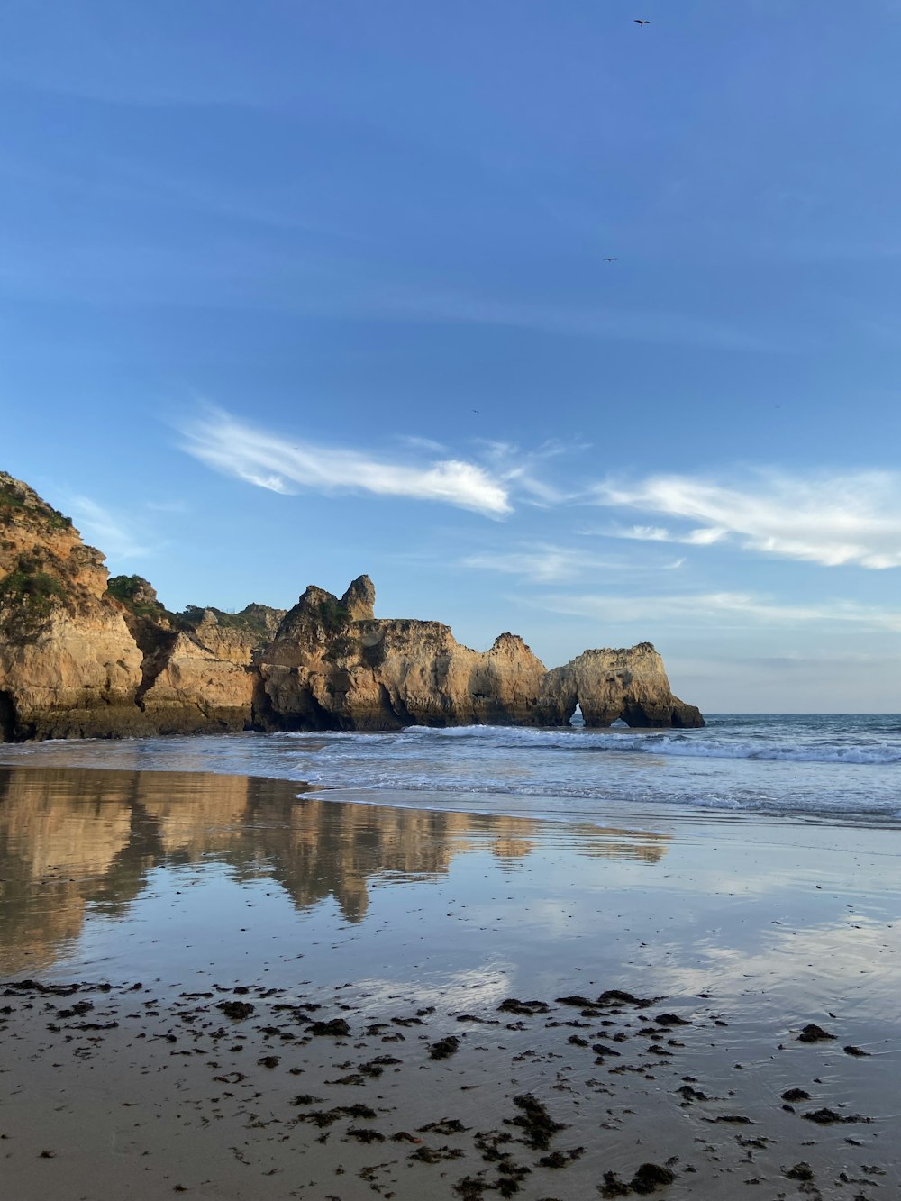 a sandy beach with a rock formation in the background