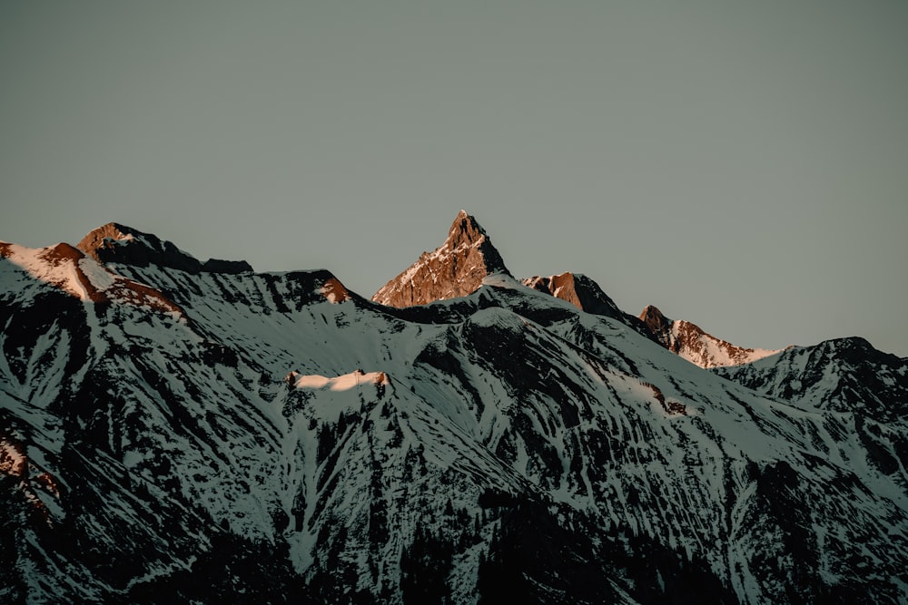 Une chaîne de montagnes enneigée sous un ciel gris