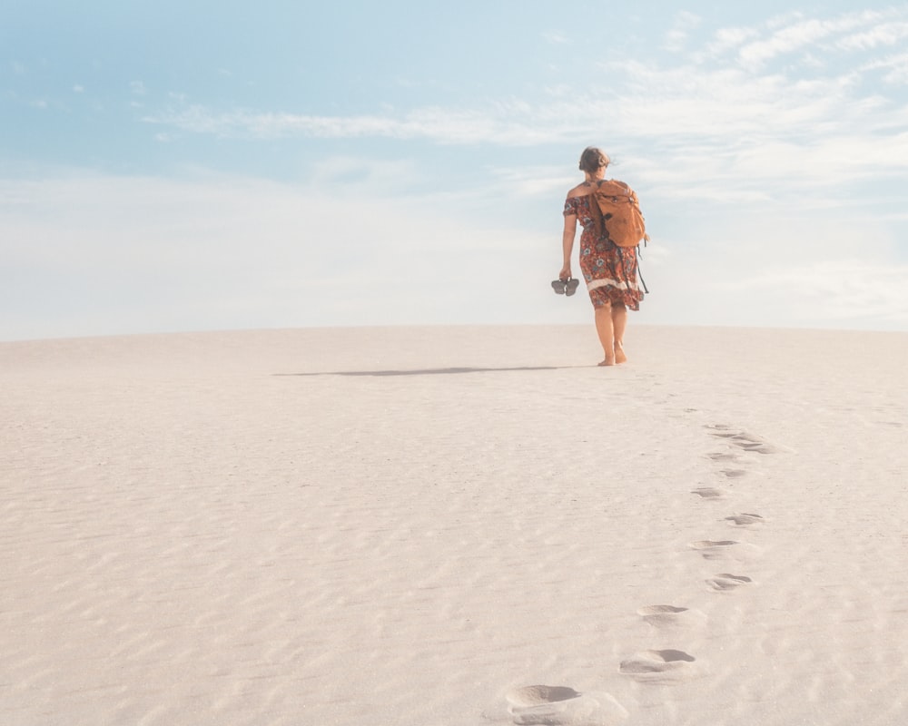 a person walking across a sandy beach