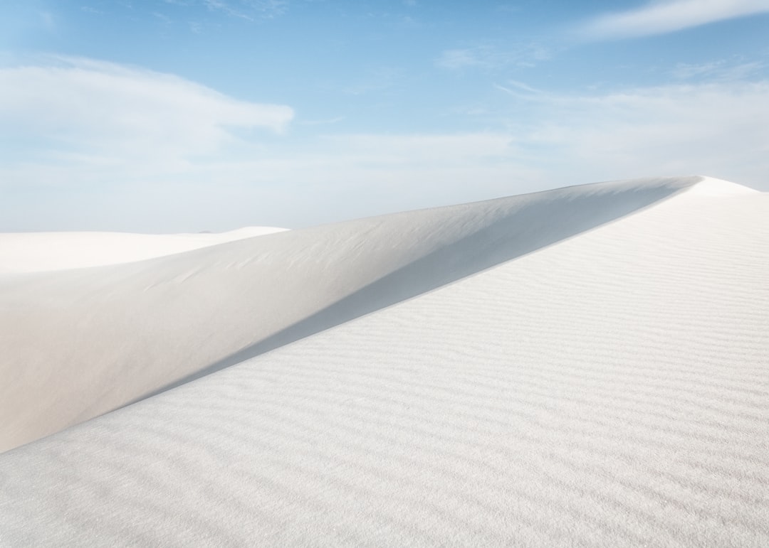 a white sand dune under a blue sky,