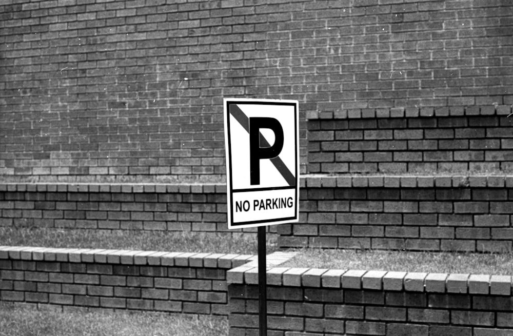 a no parking sign in front of a brick wall