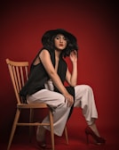 a woman sitting on a chair wearing a black hat