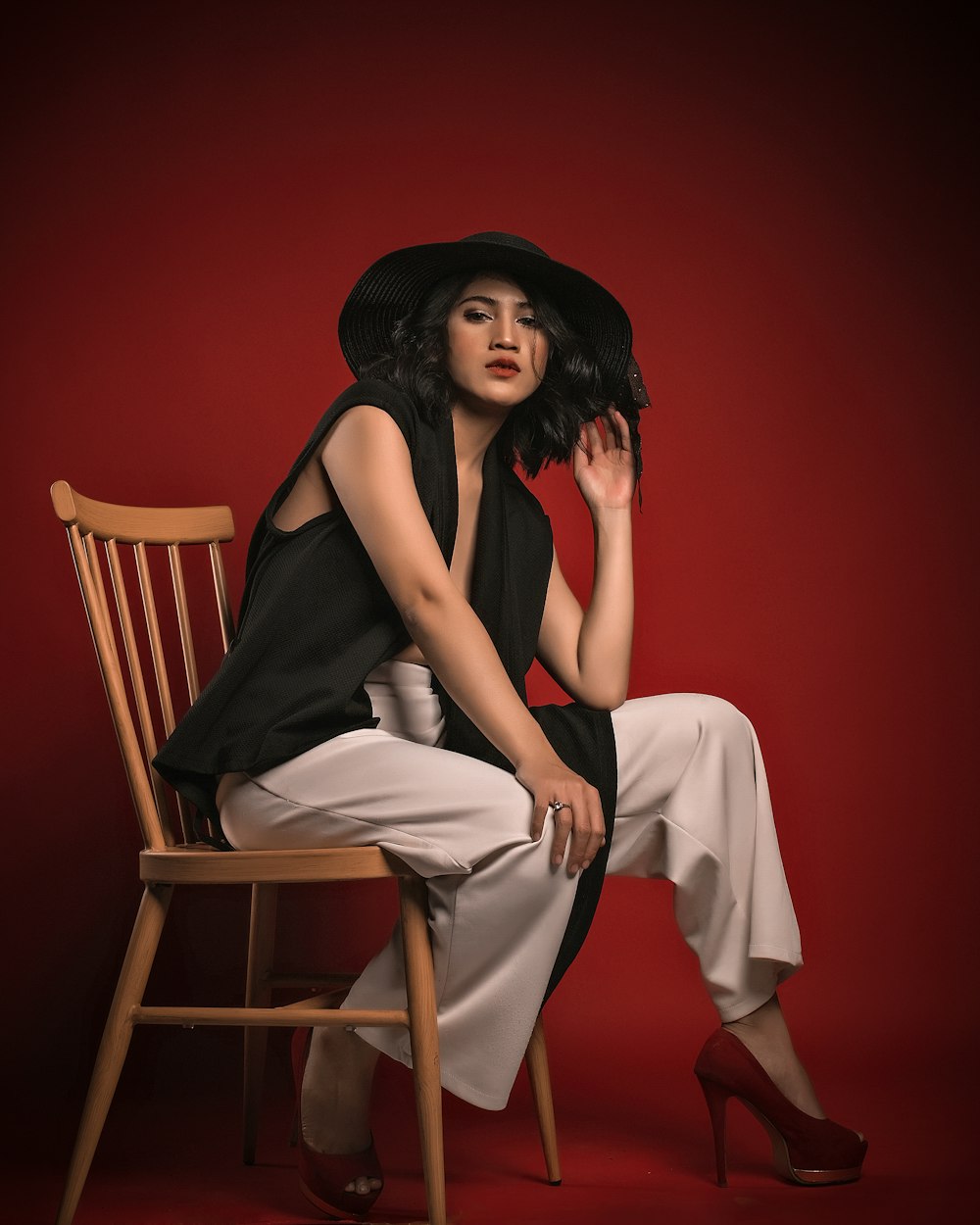 a woman sitting on a chair wearing a black hat