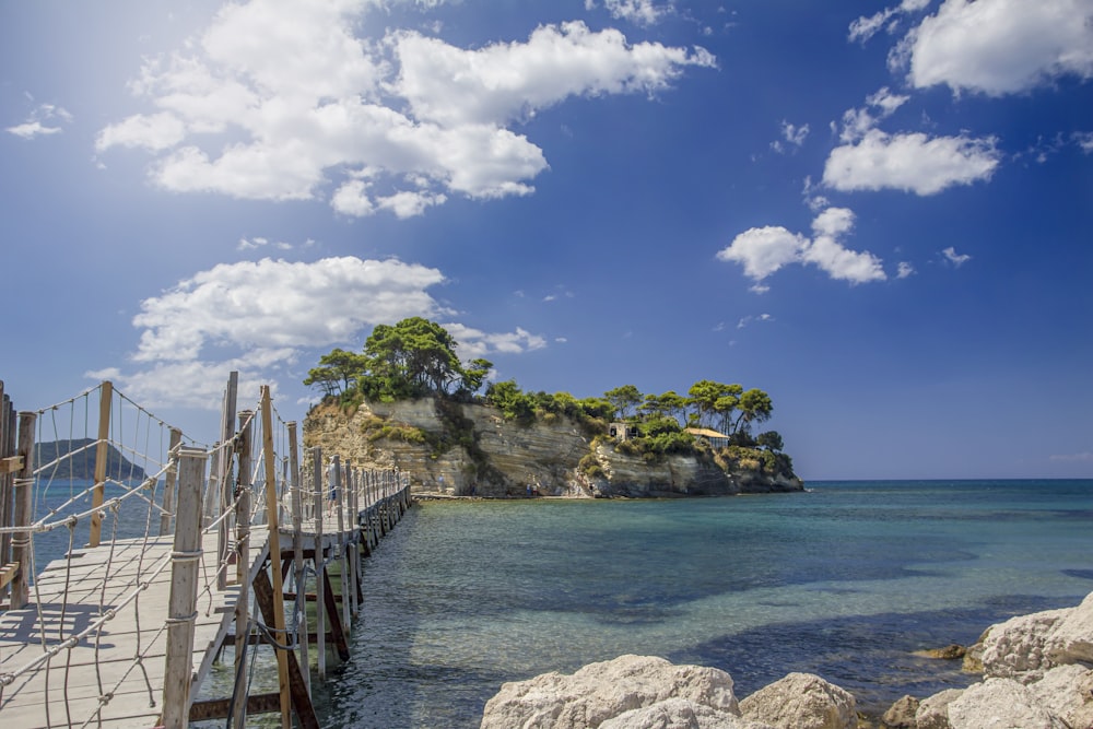 a wooden dock on the water with a small island in the background