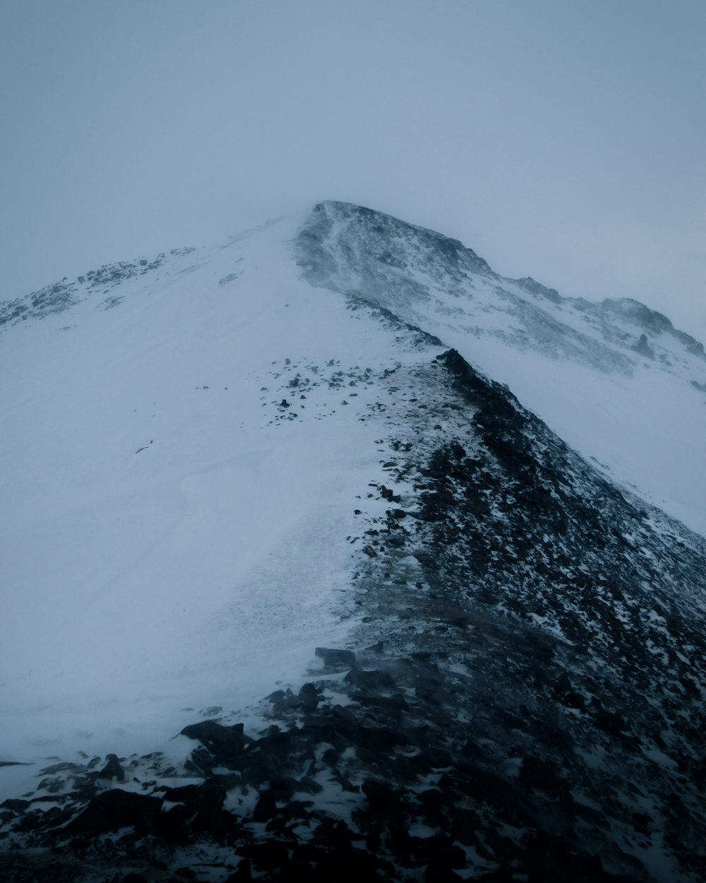 Ein sehr hoher Berg, der an einem bewölkten Tag mit Schnee bedeckt ist