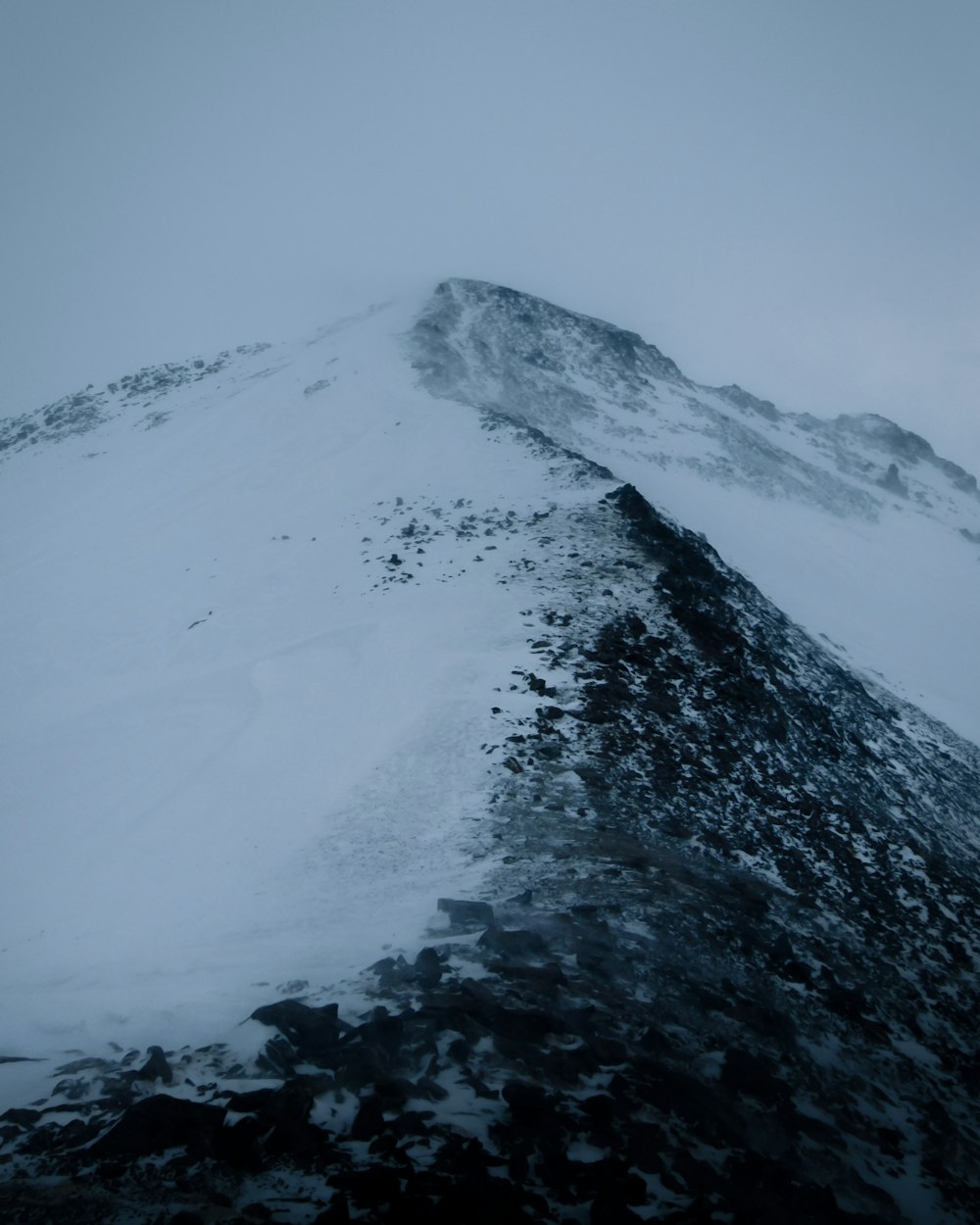 a very tall mountain covered in snow on a cloudy day