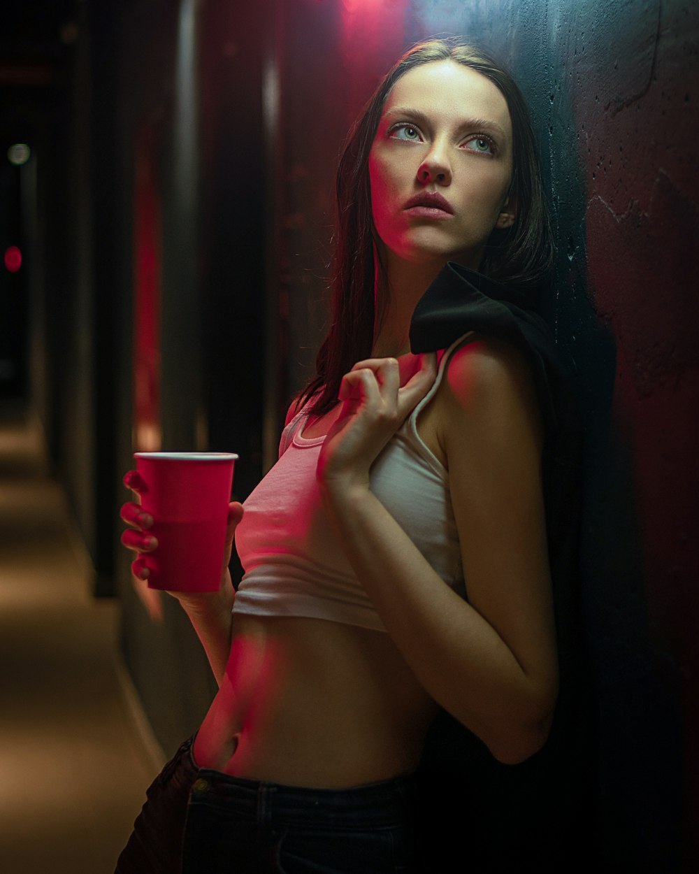 a woman holding a cup of coffee standing in a hallway