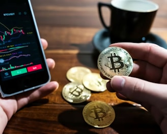 a person holding a bitcoin next to a cup of coffee