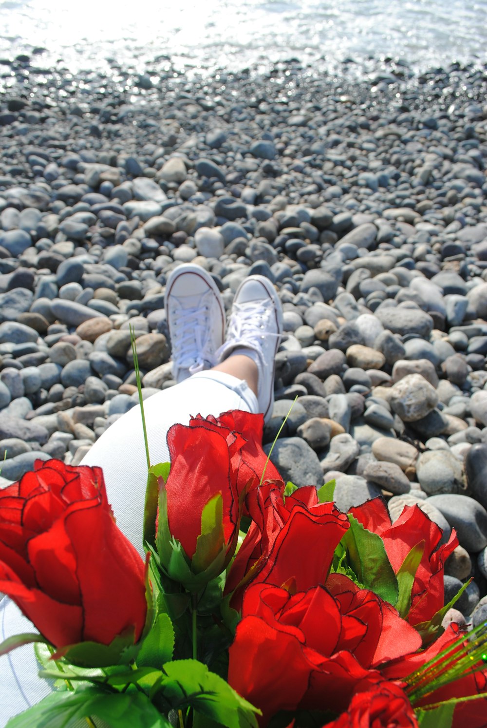 a bouquet of red roses sitting next to a person's feet