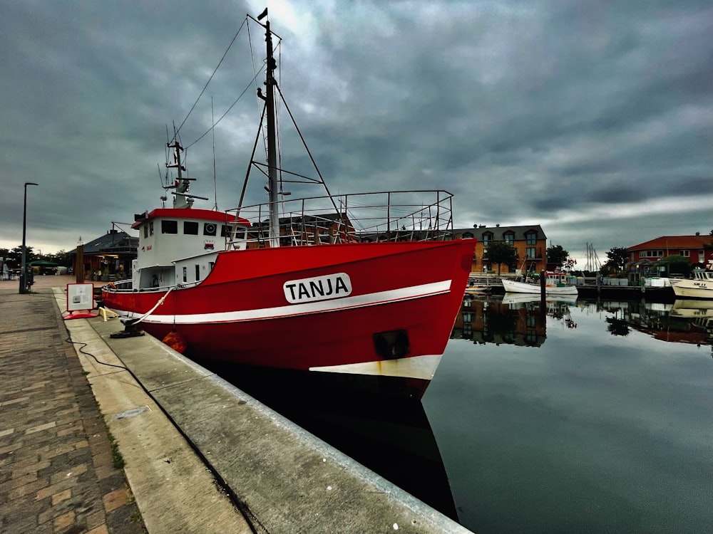 a red and white boat docked at a dock