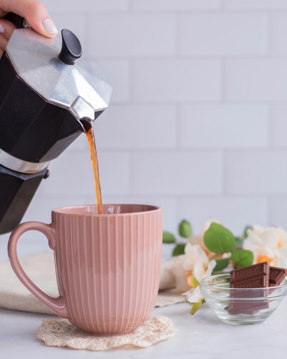 a person pours coffee into a pink mug