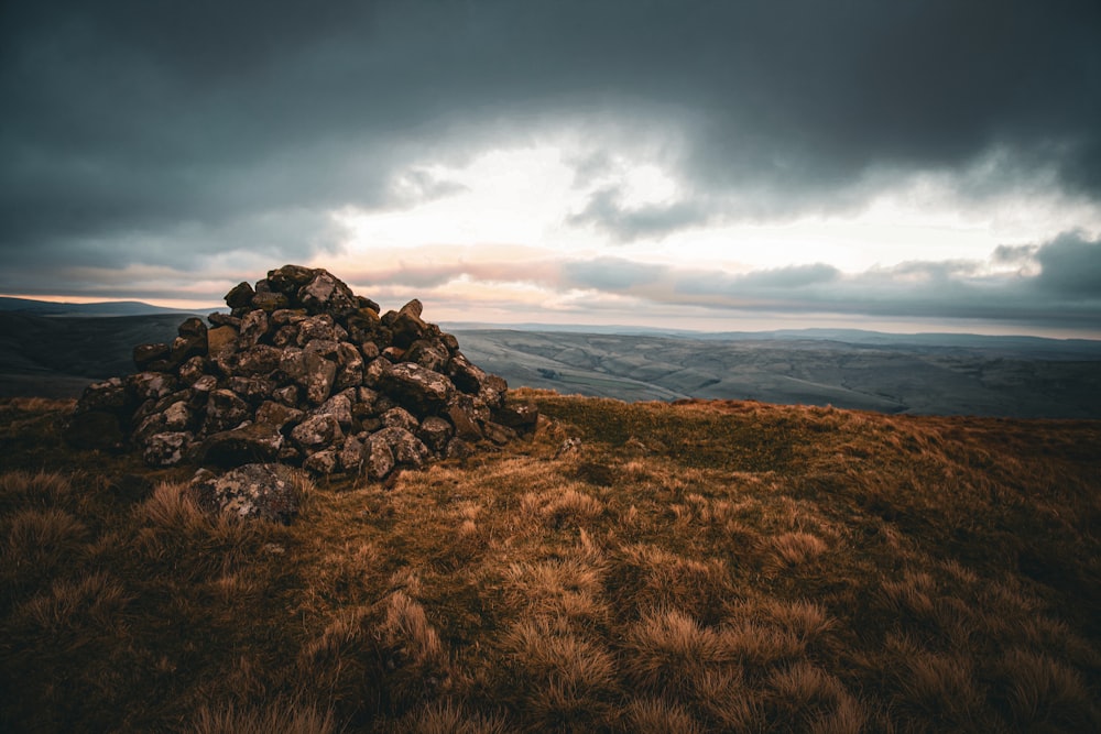 a pile of rocks sitting on top of a grass covered hillside