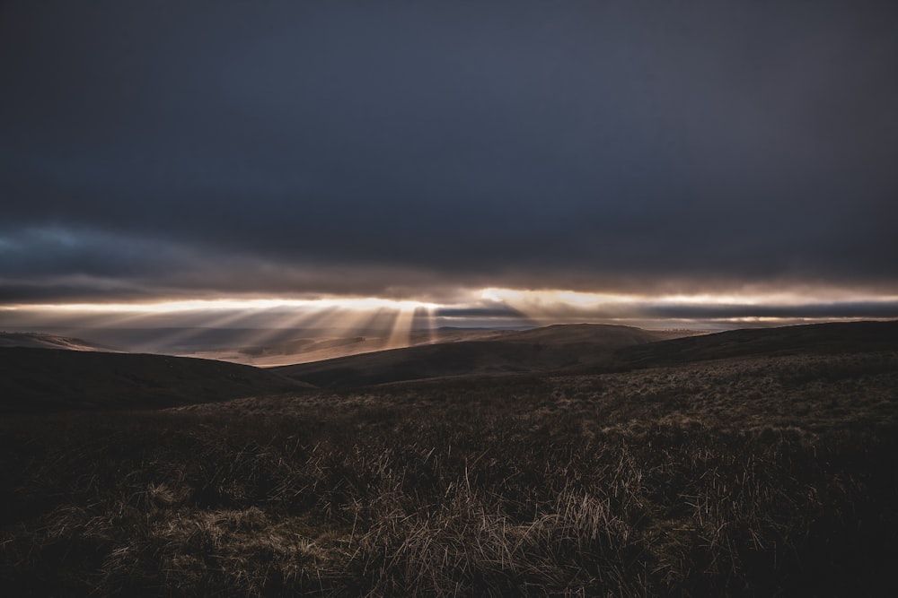 the sun shines through the clouds over the hills